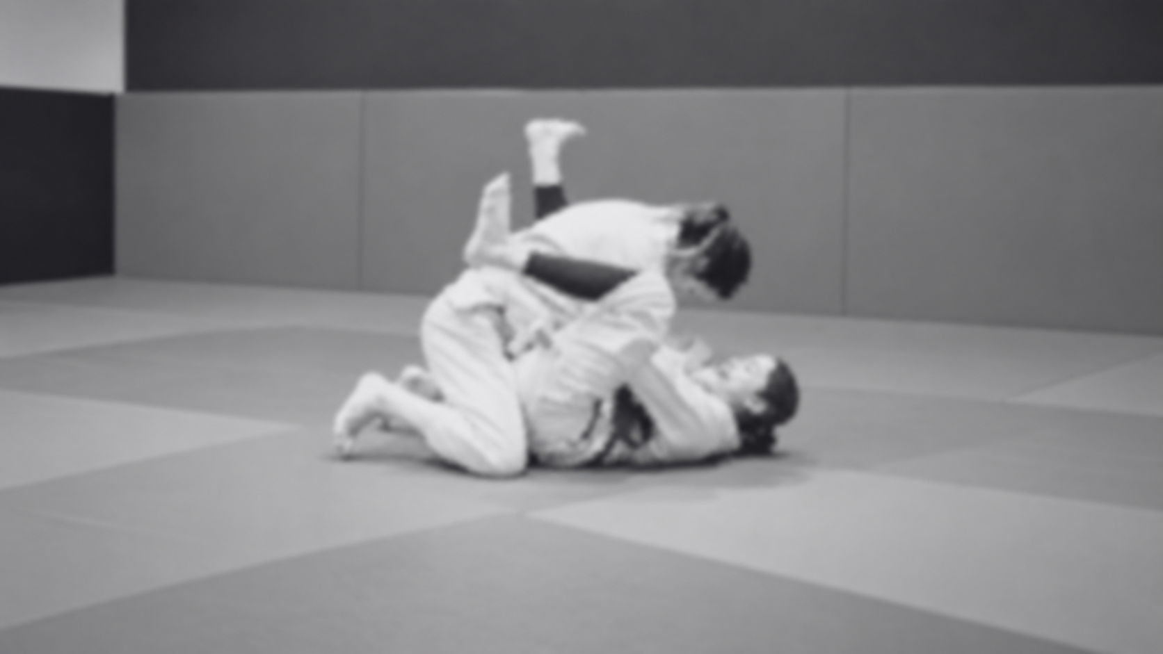 Alunos treinando jiu-jitsu no chão, em preto e branco